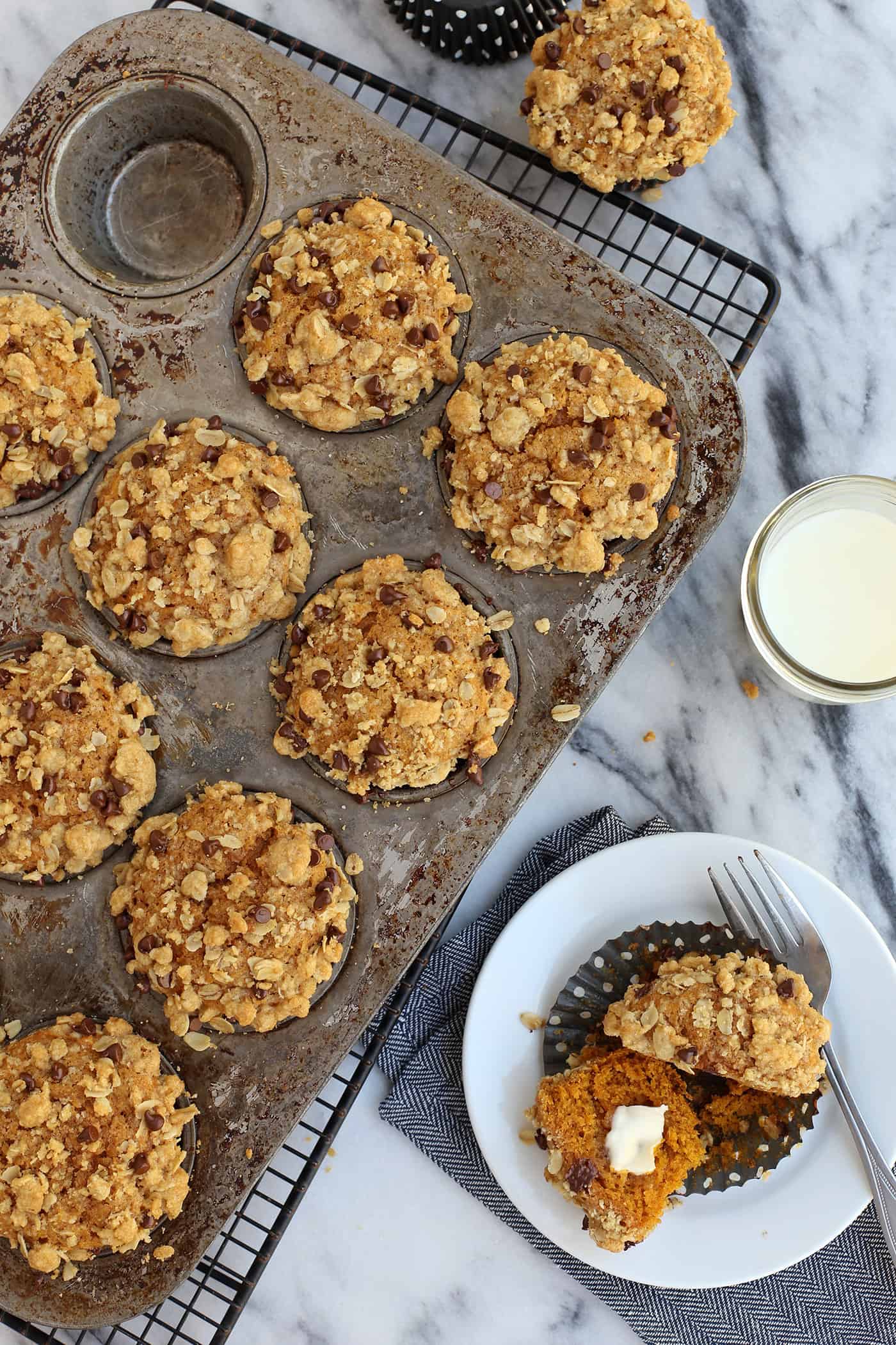 Pumpkin muffins with oatmeal chocolate chip streusel in a muffin pan with one in a dish to serve