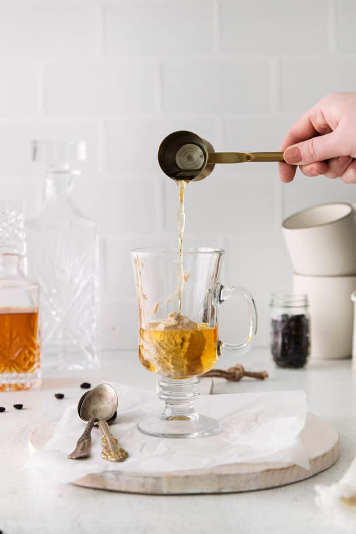 A shot of rum being poured on top of spiced butter