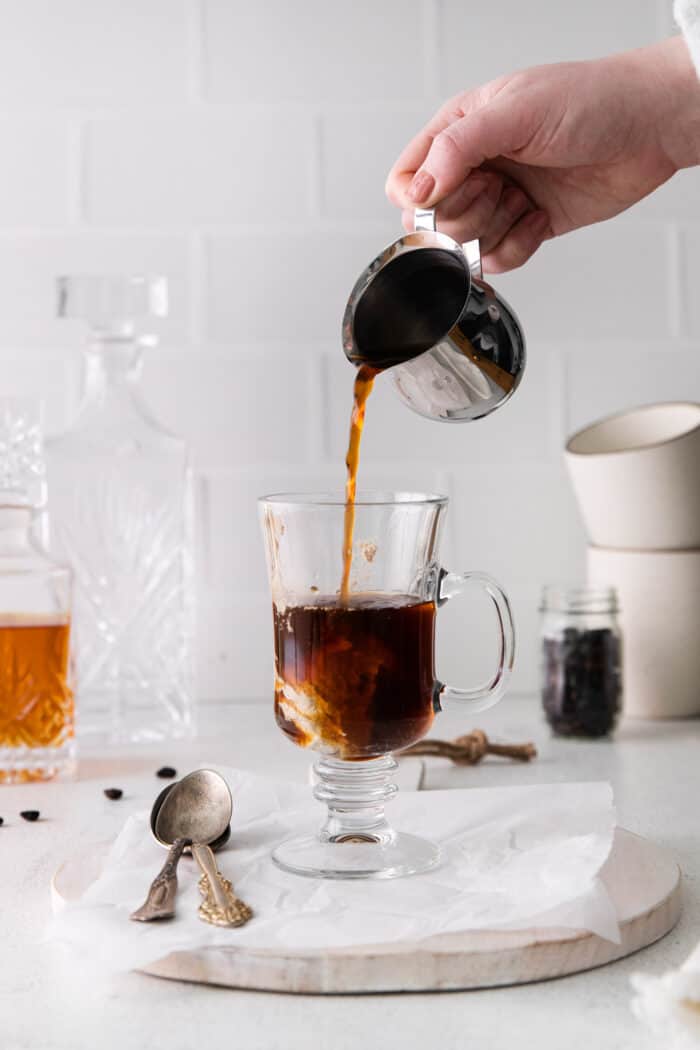 Coffee being poured into a glass with spiced butter and rum