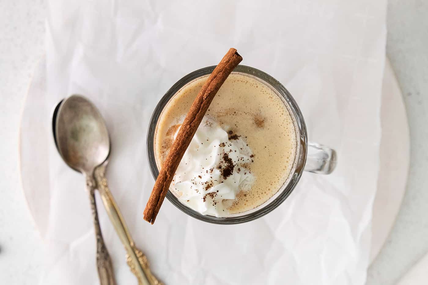 Overhead view of a hot buttered rum coffee with whipped cream and a cinnamon stick