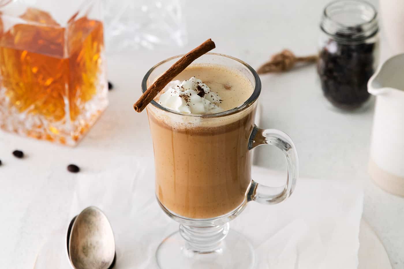 A hot buttered rum coffee cocktail with whipped cream and a cinnamon stick