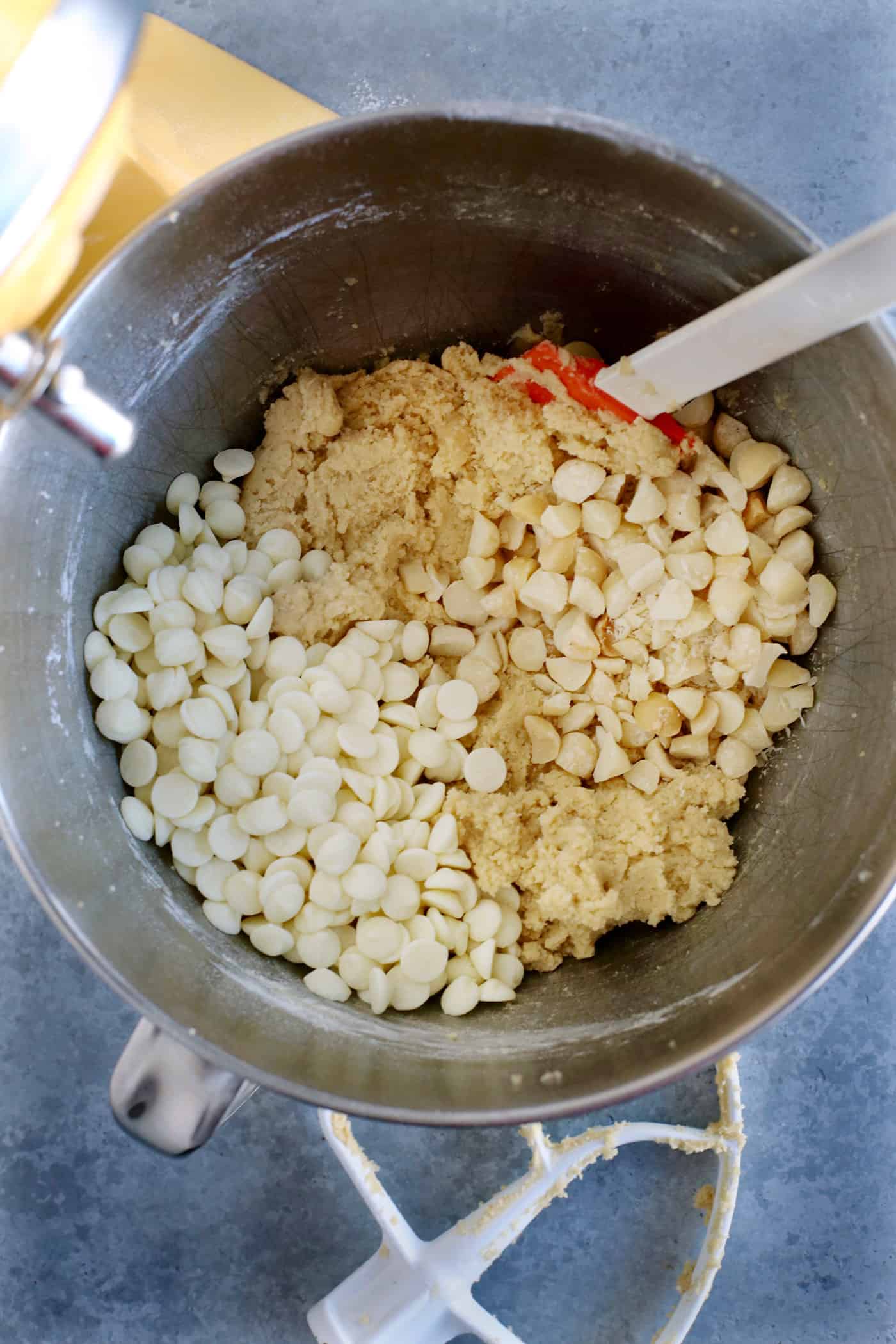 White chocolate chips and macadamia nuts being folded into cookie dough