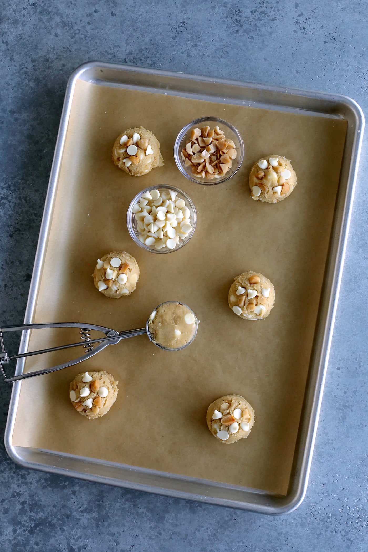 Overhead view of balls of white chocolate chip cookie dough on a baking sheet