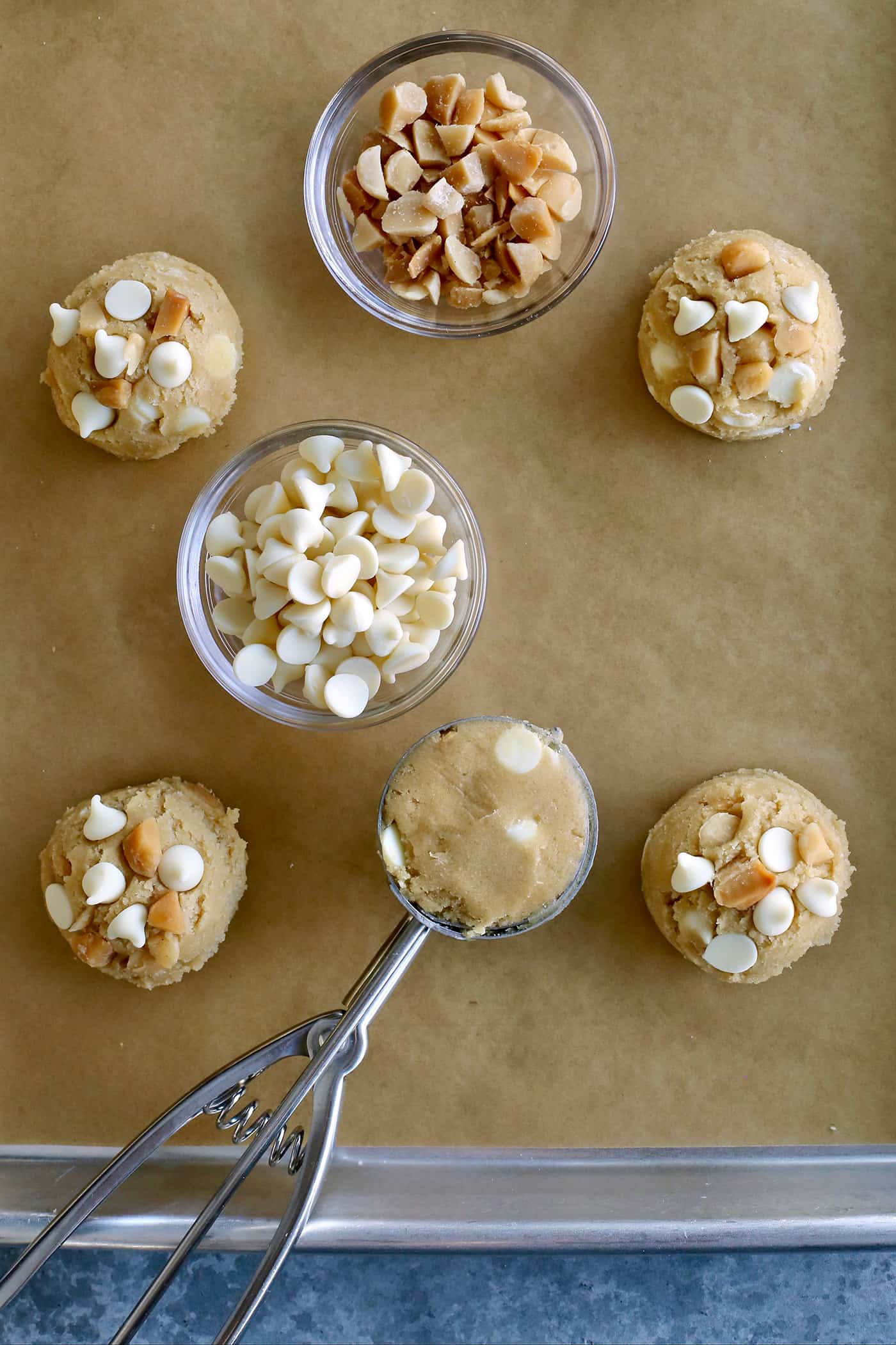 Balls of white chocolate macadamia nut cookie dough on a baking sheet