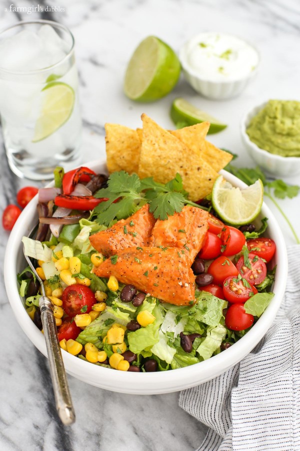 a white bowl with Santa Fe Tilapia, lettuce, corn, beans, peppers, and tomato