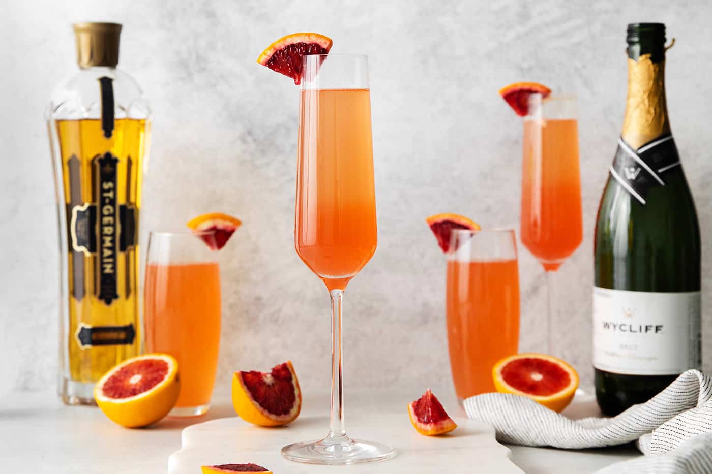 Blood orange mimosas in front of champagne and st germain bottles