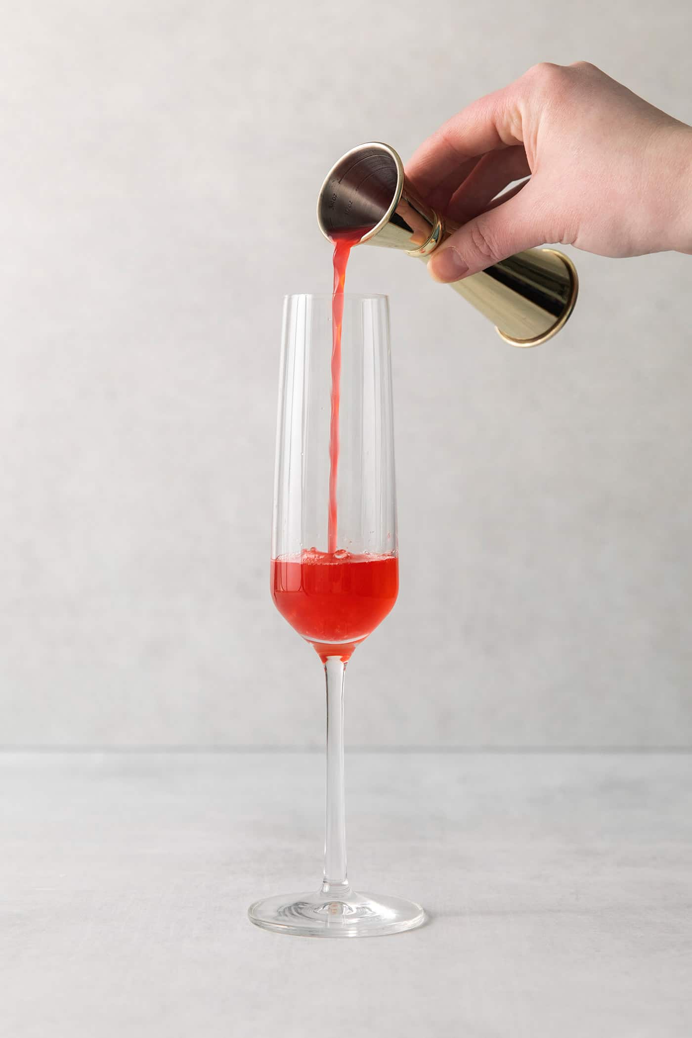 Blood orange juice being poured into a champagne flute