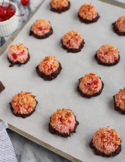 Chocolate dipped cherry macaroons on a baking sheet