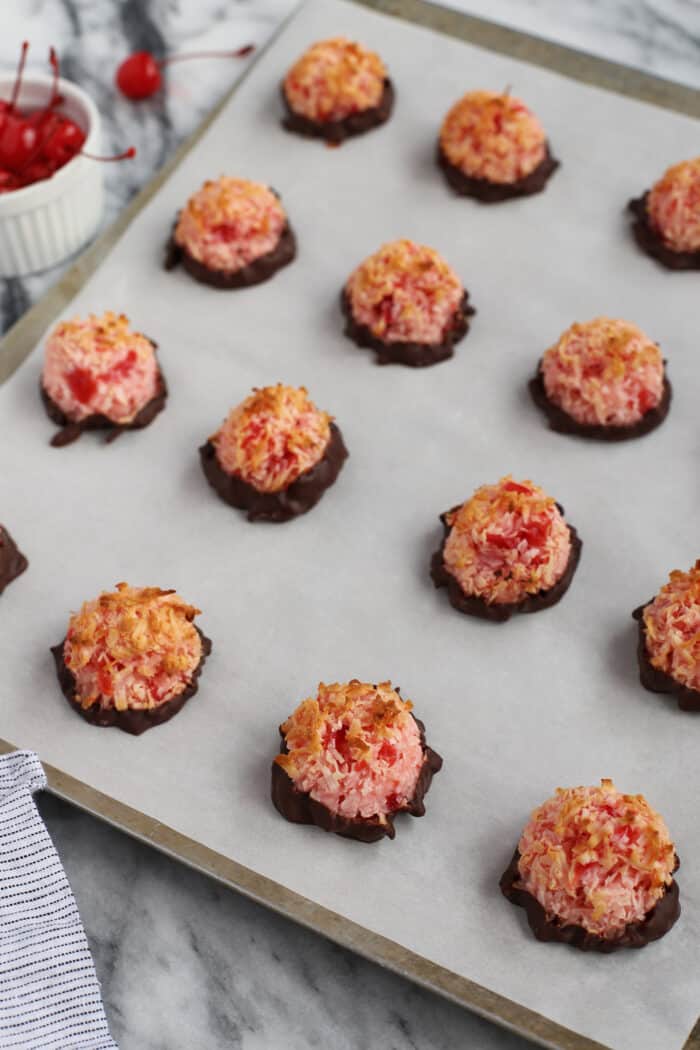 Chocolate dipped cherry macaroons on a baking sheet