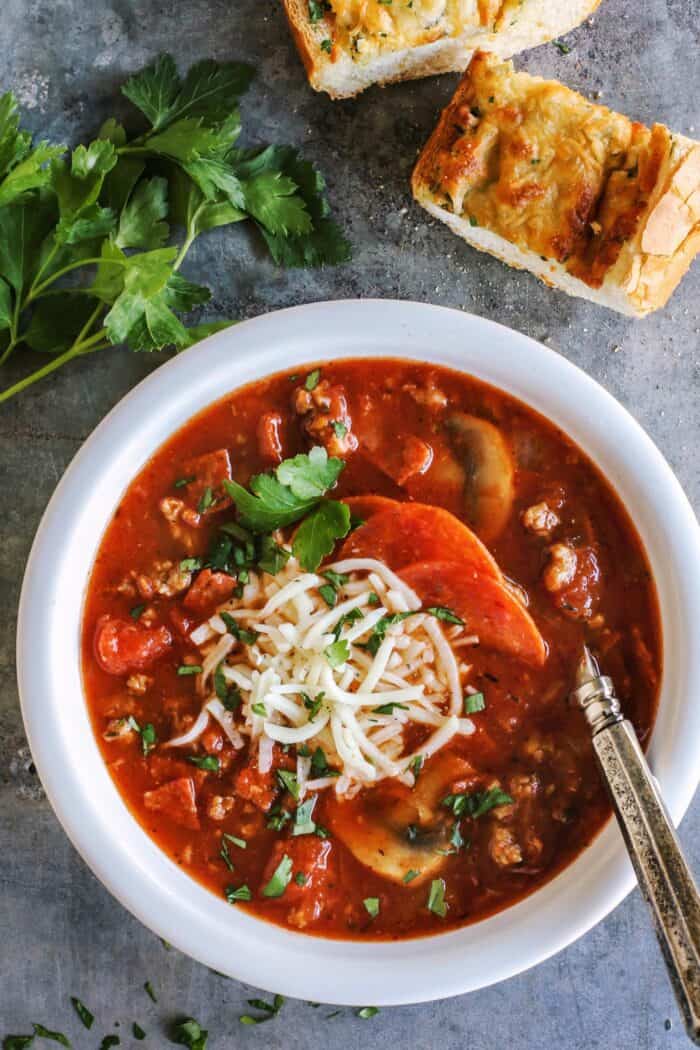 a bowl of pizza soup and cheesy bread