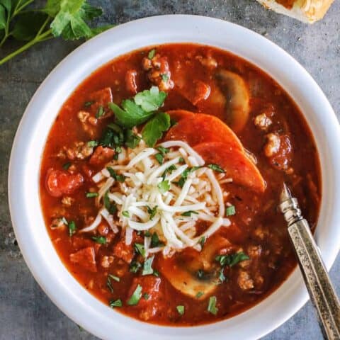 pizza soup in a bowl with shredded cheese