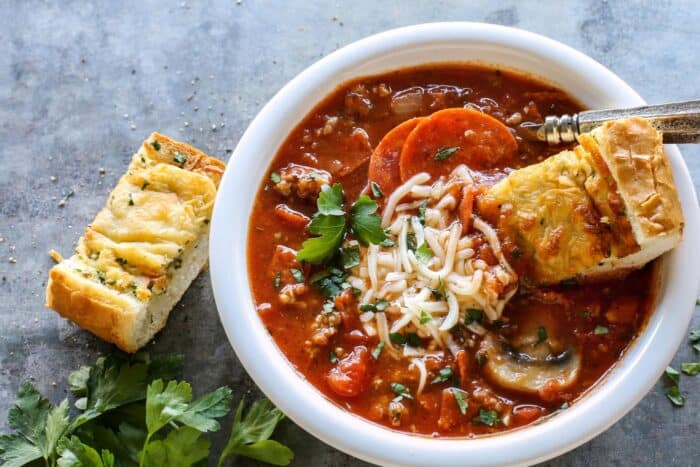 dipping cheesy garlic bread into a bowl of pizza soup