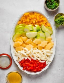 Bell peppers, apples, pineapple, and fennel arranged on platter.