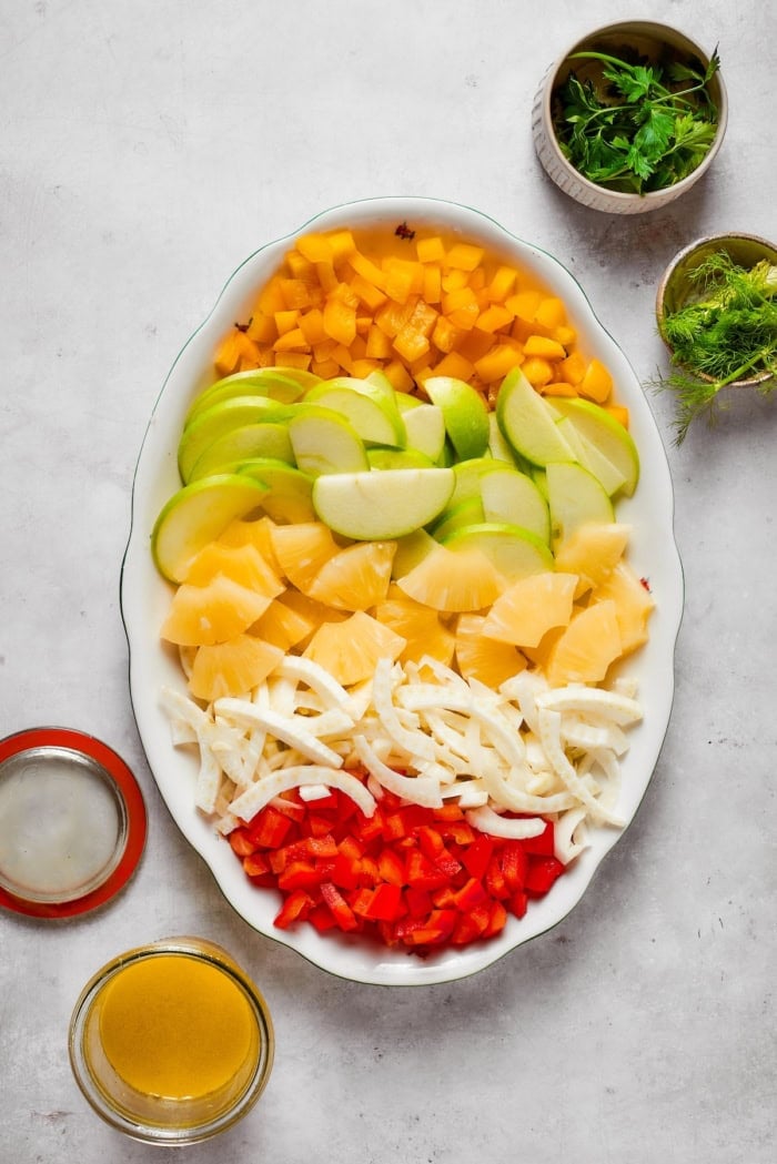 This fresh, crisp Fennel Apple Salad with pineapple, bell peppers and ginger dressing is an easy, vibrant side dish perfect for any meal! Bell peppers, apples, pineapple, and fennel arranged on platter.