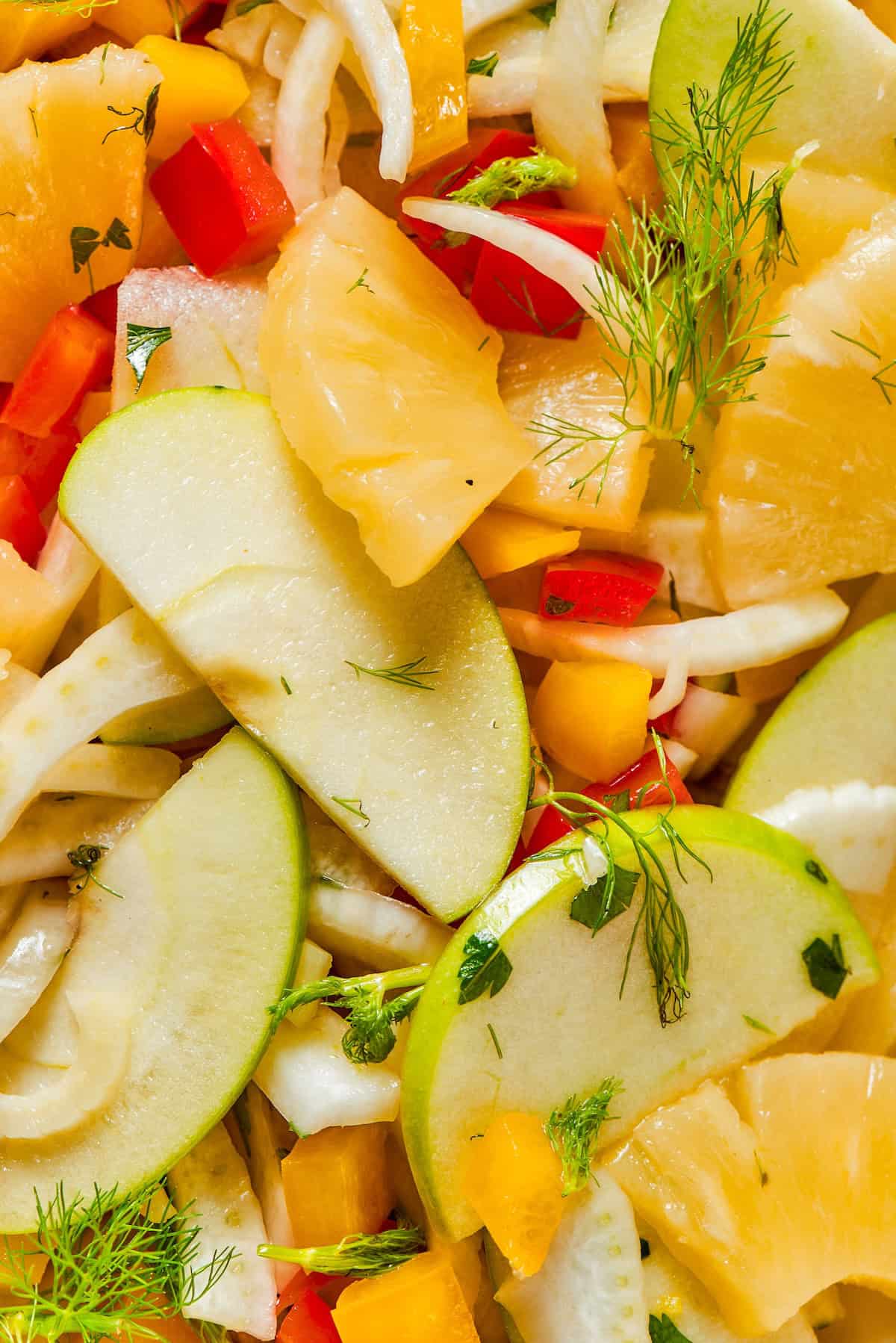 This fresh, crisp Fennel Apple Salad with pineapple, bell peppers and ginger dressing is an easy, vibrant side dish perfect for any meal! Closeup view of fennel apple salad with pineapple and bell peppers.