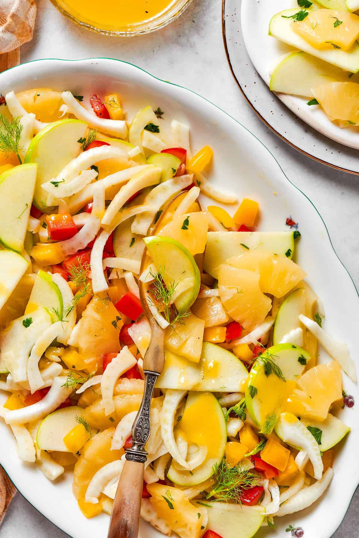 This fresh, crisp Fennel Apple Salad with pineapple, bell peppers and ginger dressing is an easy, vibrant side dish perfect for any meal! Platter of fennel apple salad with pineapple and ginger dressing.