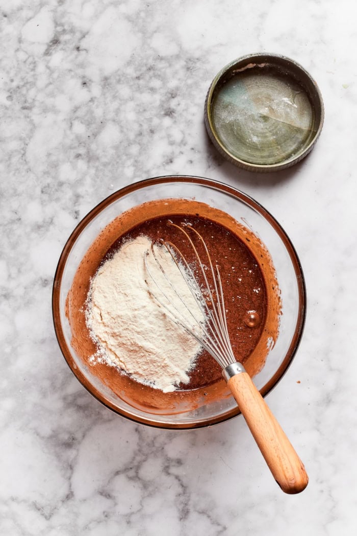 Whisk in bowl with flour and wet ingredients for brownies.