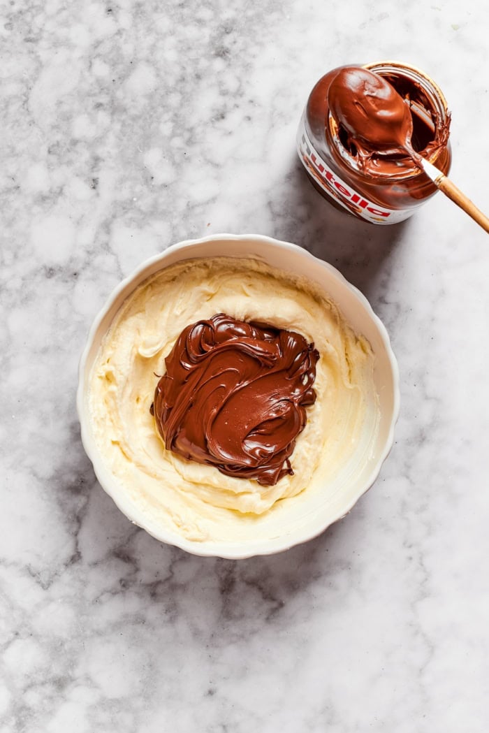 Nutella added to cheesecake mixture in bowl.