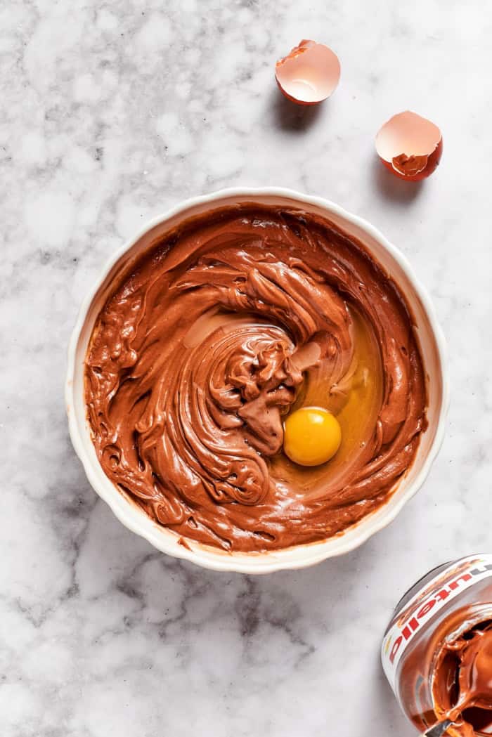 Egg cracked into Nutella cheesecake mixture.