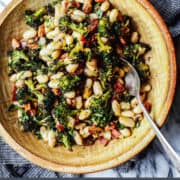 pinterest image of a pottery bowl with great northern white beans, roasted broccoli, fried bacon, and lemon zest