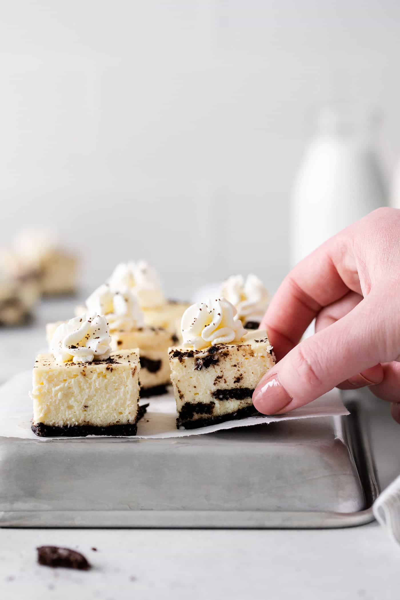 A hand grabbing an oreo cheesecake bite