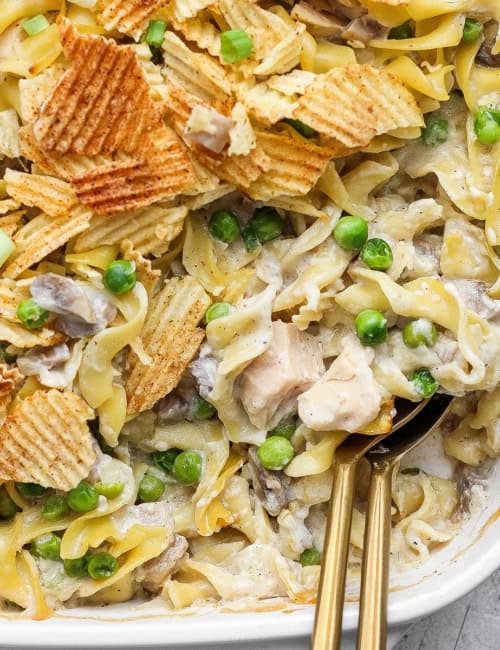 Two spoons in dish of sour cream and onion tuna noodle casserole.