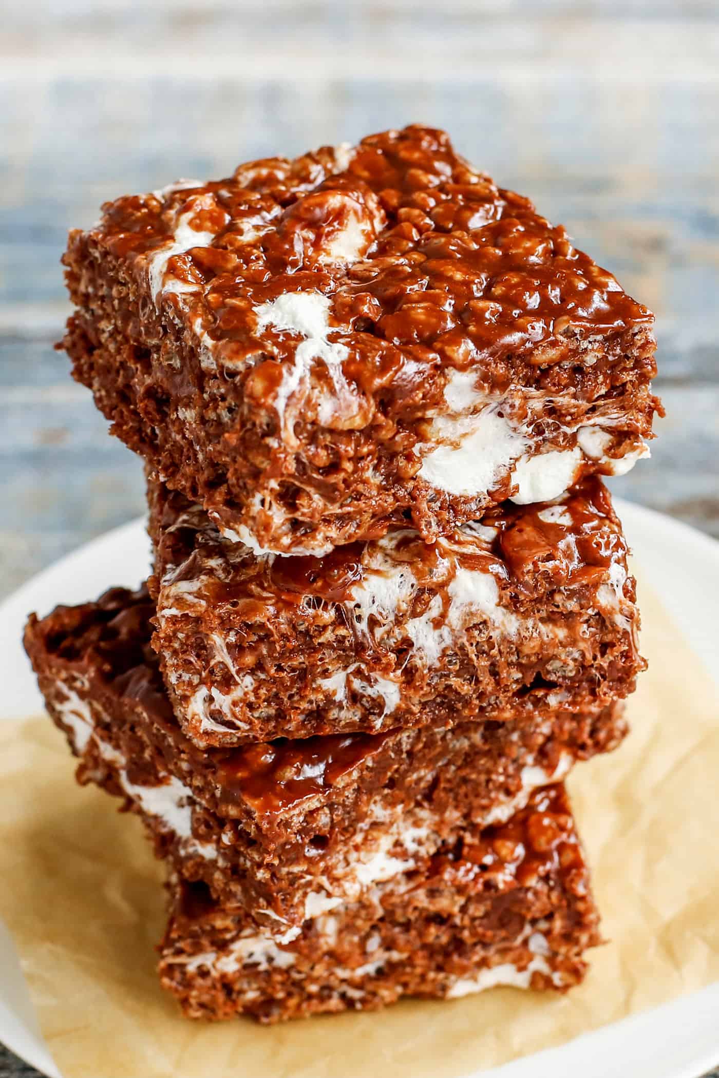A close-up of 3 chocolate peanut butter rice krispies bars stacked on a plate