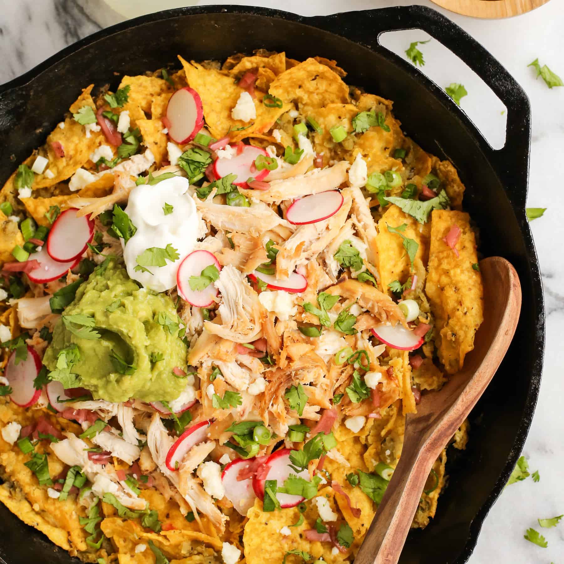 Skillet chicken chilaquiles topped with radishes and guacamole