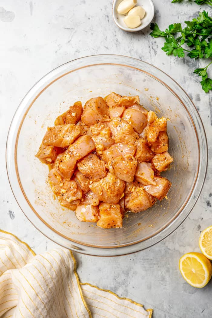 These Grilled Lemon Pepper Chicken Skewers are an easy summer recipe that's super fast for a weeknight. Don't skip the lemon butter sauce! Chicken in bowl of lemon pepper marinade