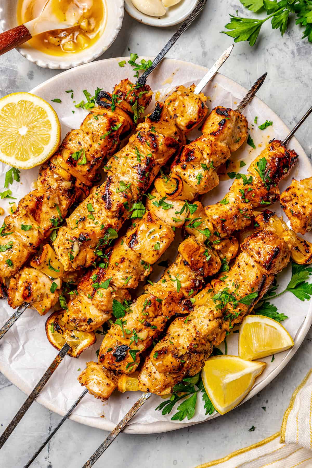 These Grilled Lemon Pepper Chicken Skewers are an easy summer recipe that's super fast for a weeknight. Don't skip the lemon butter sauce! Grilled lemon pepper chicken skewers on platter with lemon wedges