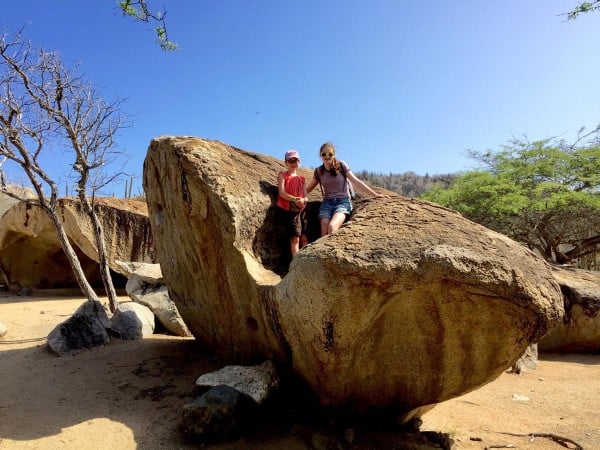 two girls sitting on a large rock