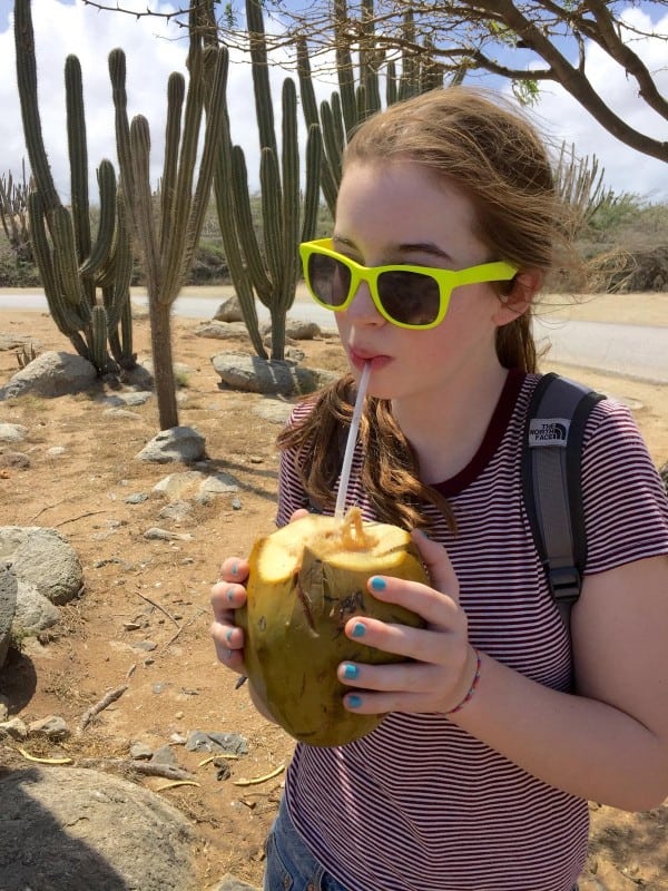 a girl drinking from a fresh coconut