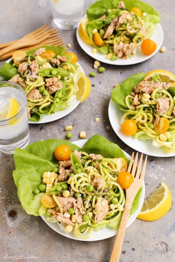 Lemon Pepper Salmon and Zucchini Noodle Salad Cups on plates with glasses of lemon water