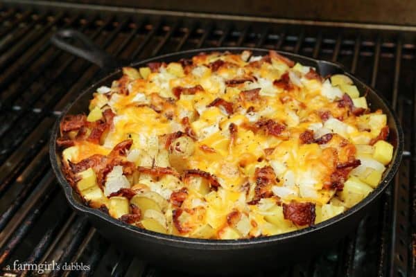 Cheesy Grilled Skillet Potatoes with Bacon and Herbs on a grill