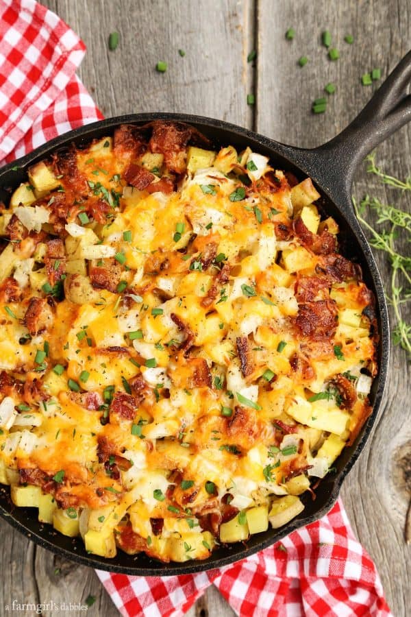 Cheesy Grilled Skillet Potatoes with Bacon and Herbs on a wood table with a red checked napkin