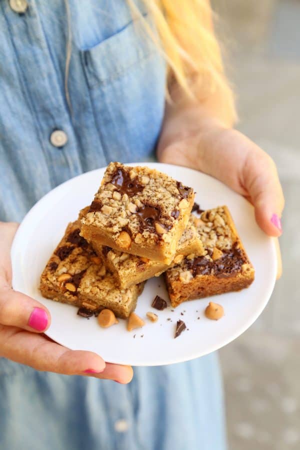 a girl holding a plate of Butterscotch Chocolate Chunk Blondies