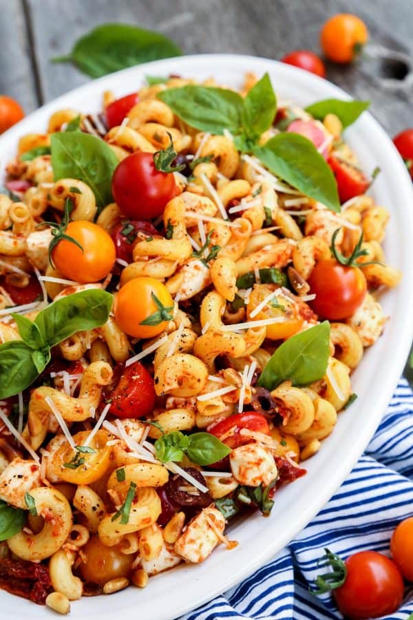 Pasta salad with sun dried tomatoes in a large, white dish