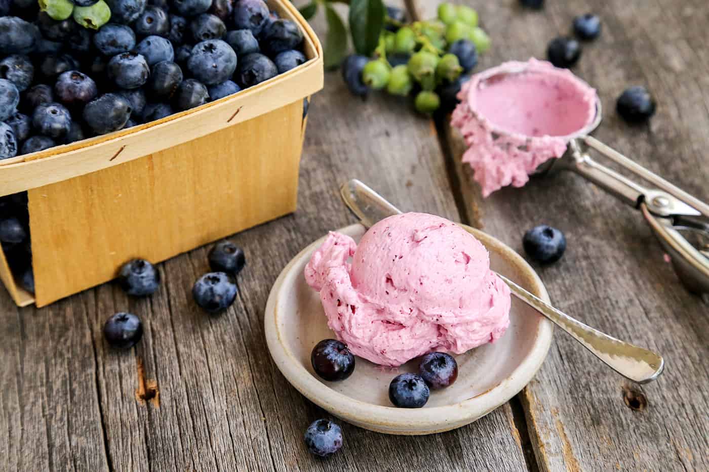 A scoop of whipped butter with blueberries and the scoop in the background