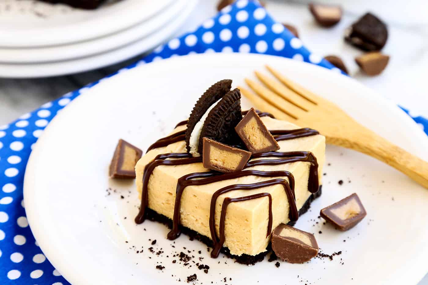 No bake chocolate peanut butter cheesecake bars topped with oreo and peanut butter cups