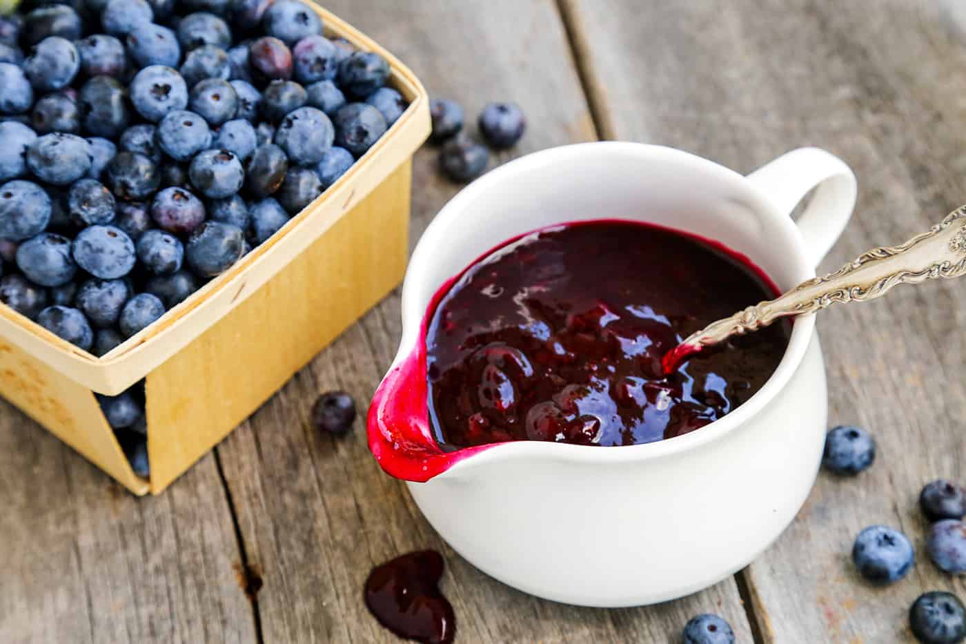 A bowl of blueberry sauce with a pint of blueberries