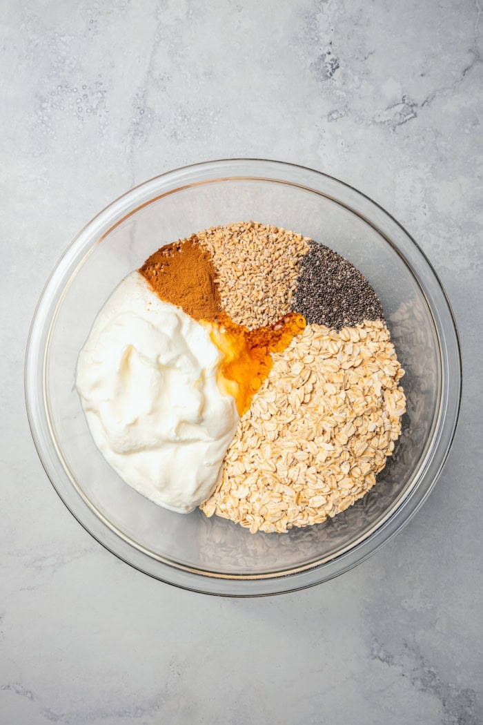 Overhead view of ingredients for apple cinnamon overnight oats in bowl before stirring