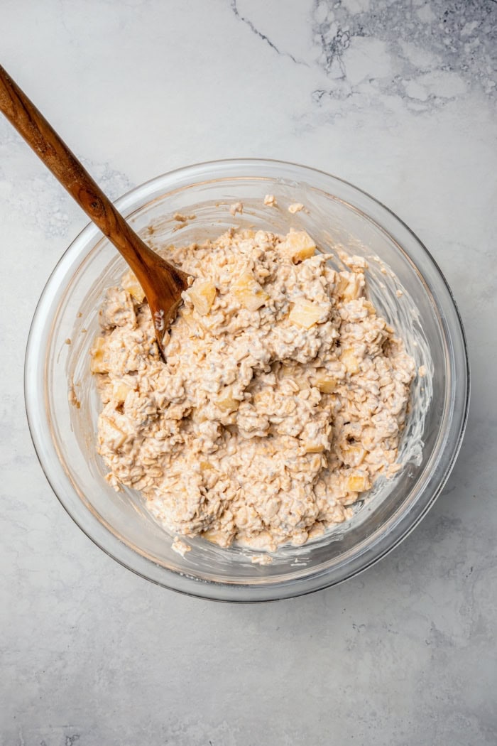 Overhead view of overnight oats mixture in bowl with wooden spoon