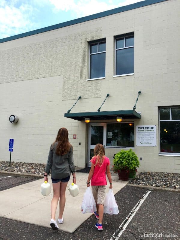 two girls carrying food into a food bank