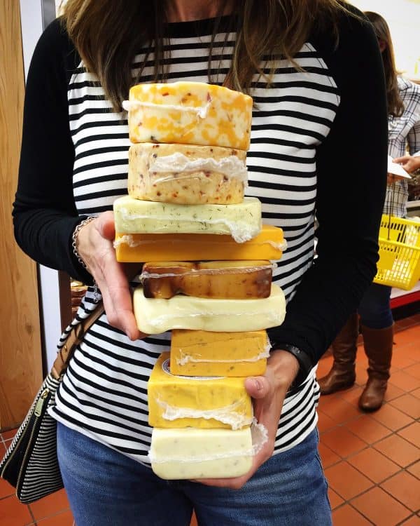 a woman holding a large stack of Pearl Valley Cheese from Ohio