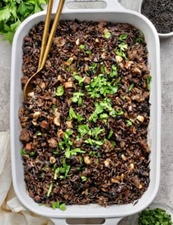 Creamy wild rice casserole in baking dish with two spoons for serving.