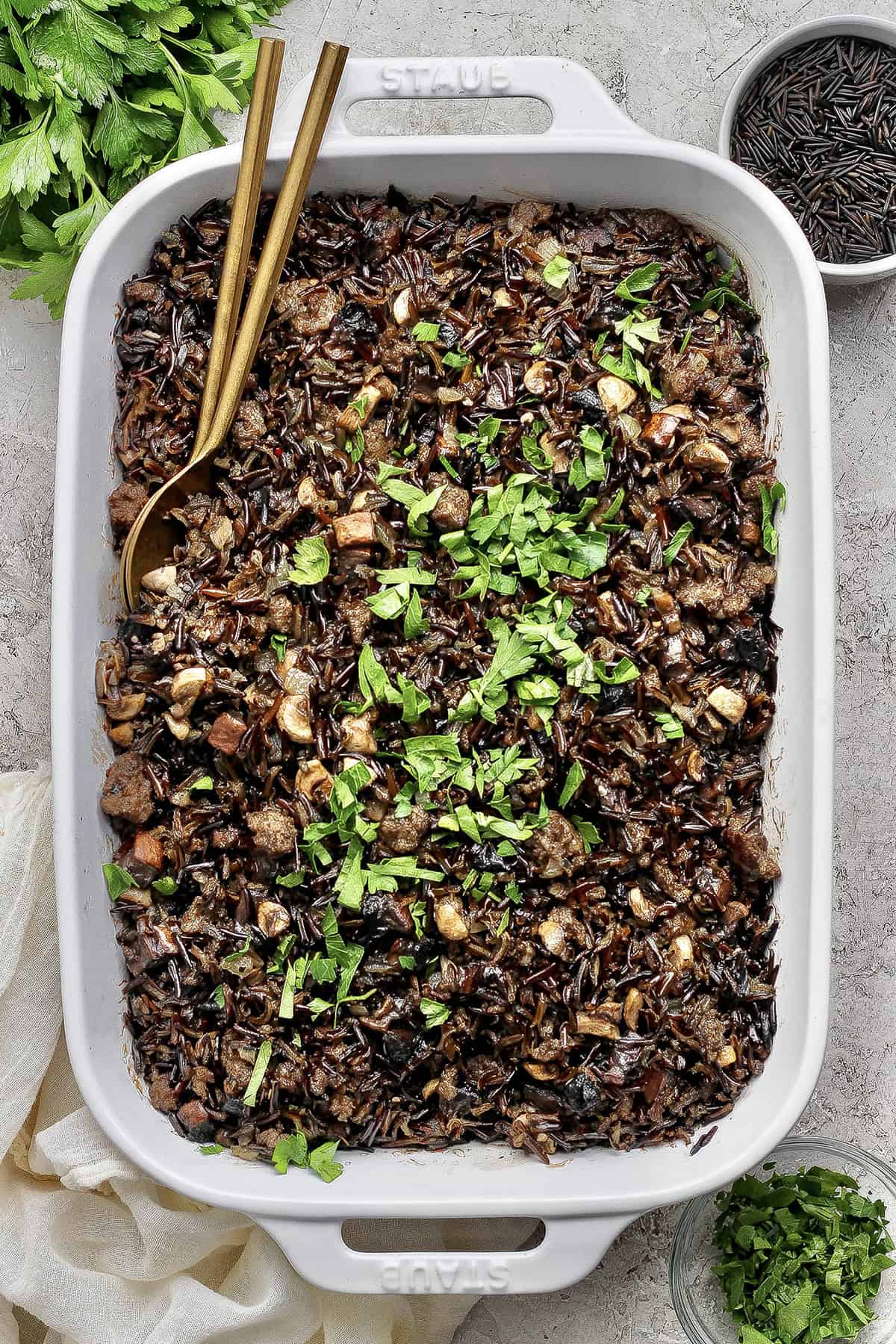 Creamy wild rice casserole in baking dish with two spoons for serving.
