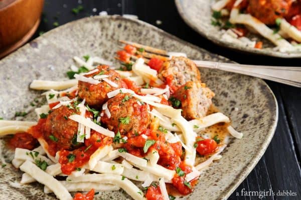 Spicy Italian Sausage Meatballs over Egg Noodles on a black counter