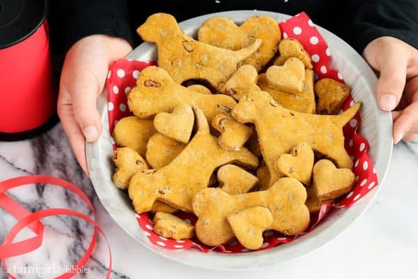 hands holding a pan of Homemade Pumpkin Bacon Dog Treats