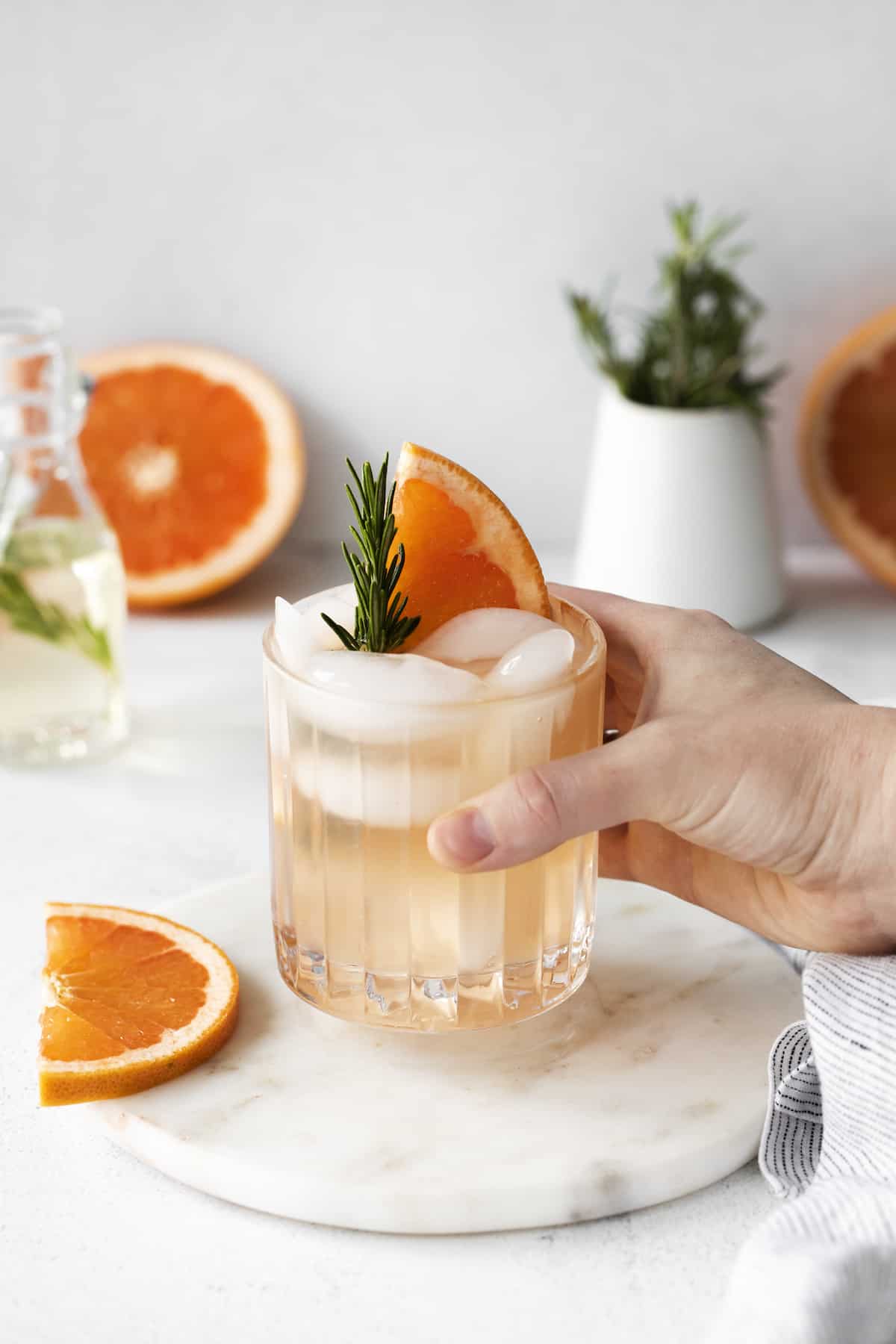 A hand holding a rosemary greyhound cocktail