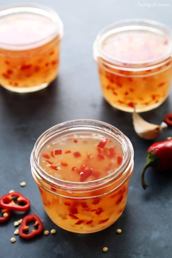 three jars of sweet chili sauce, plus red chili peppers and garlic